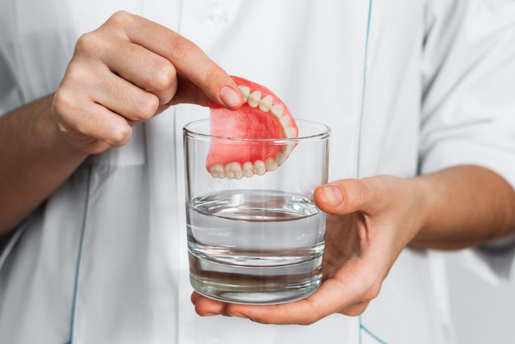 The prosthesis is in a glass with a solution. Dental prosthesis care