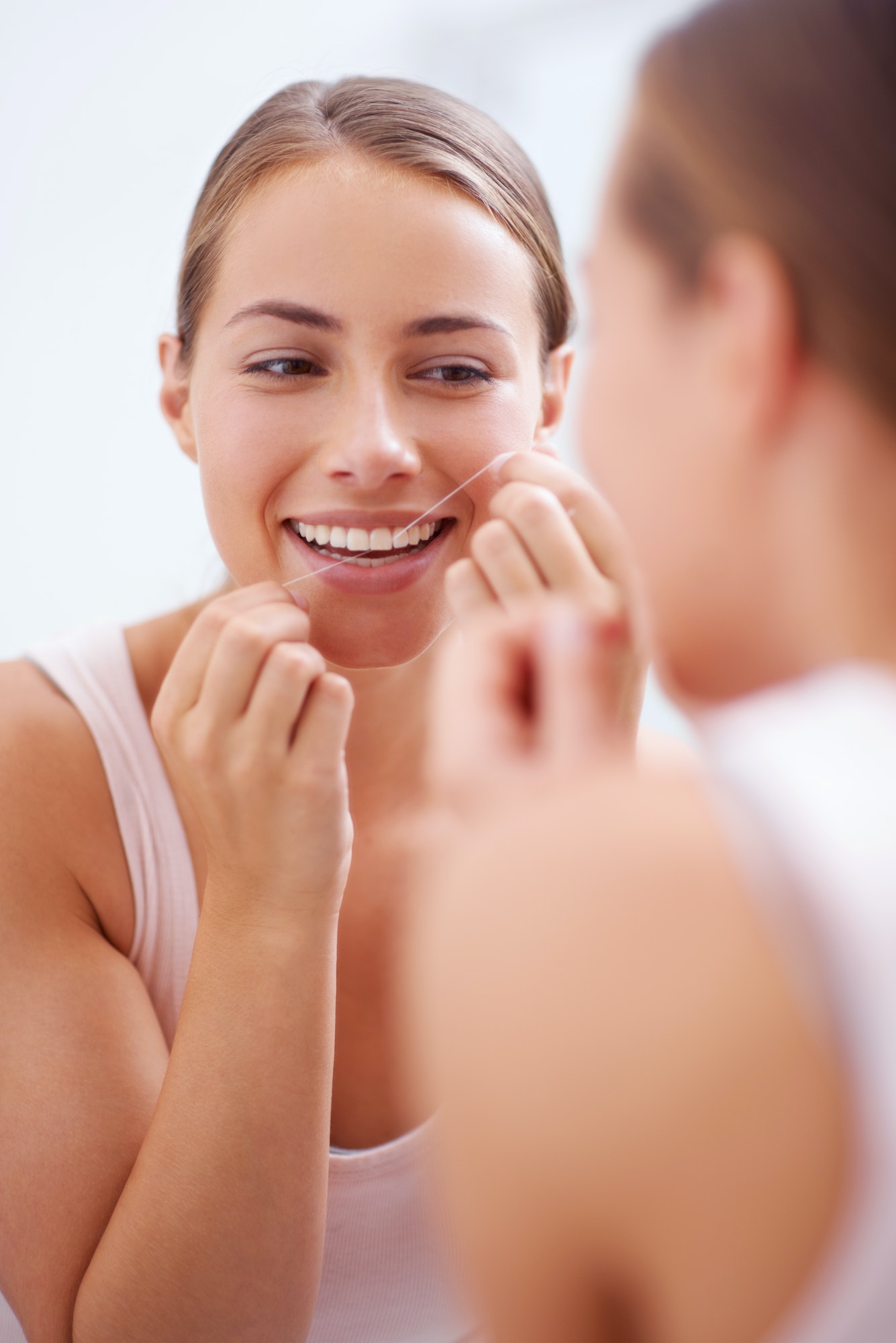 Dental hygiene is a priority. A young woman flossing her teeth.