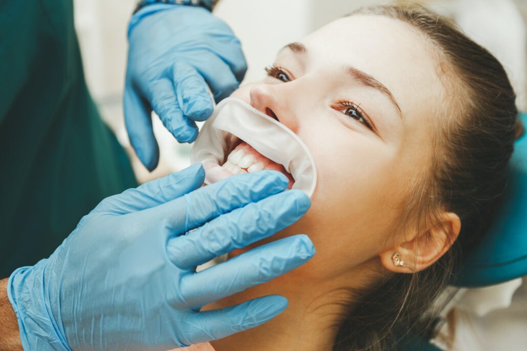 Doctor dentist puts the retractor to the patient. Close up