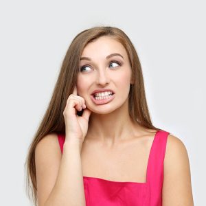 Portrait of frustrated young woman clenching teeth.